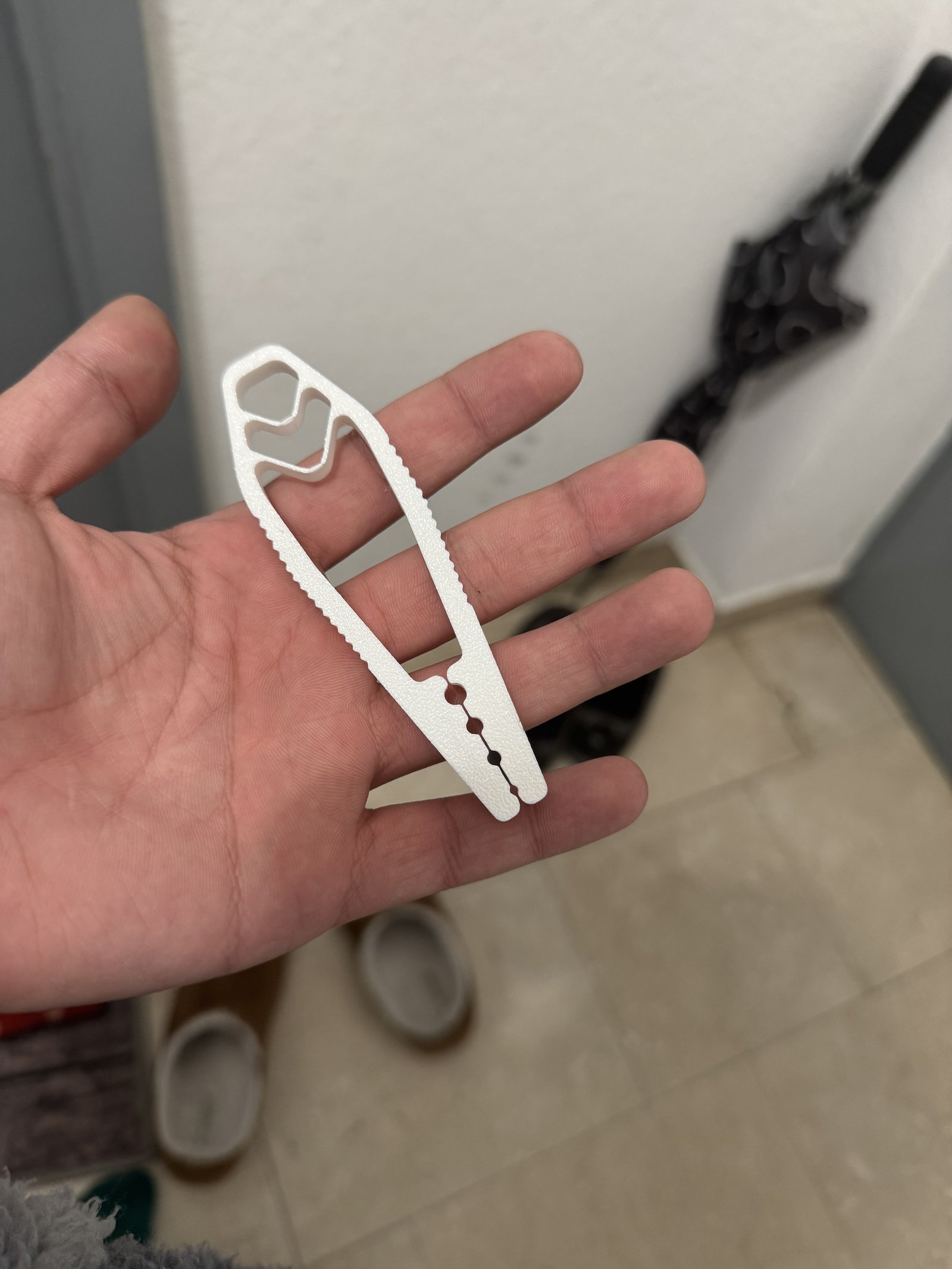 A white 3D printed clip with a serrated edge held in an open hand